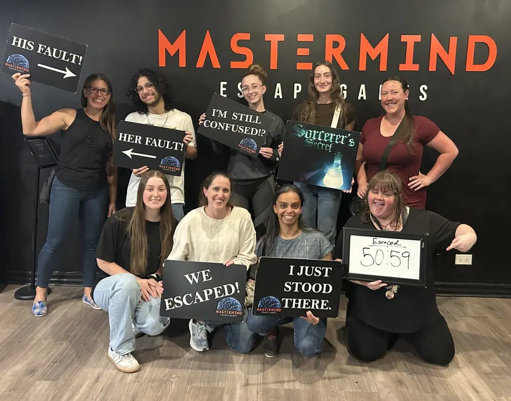 A team holding “His fault!”, “Her fault!” and Sorcerer’s Secret signs, with an escape time of 50:59